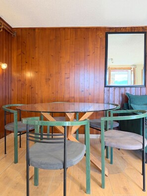 A room with a round glass table surrounded by chairs, wooden walls, and a large mirror. - A fully equipped chalet with a magnificent view of the Alps! (Crans-Montana)
