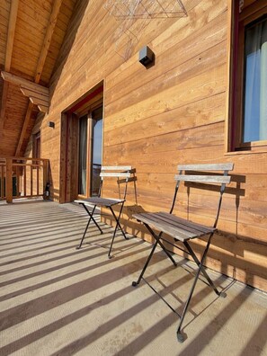 A wooden cabin with two folding chairs on a covered porch. - A fully equipped chalet with a magnificent view of the Alps! (Crans-Montana)