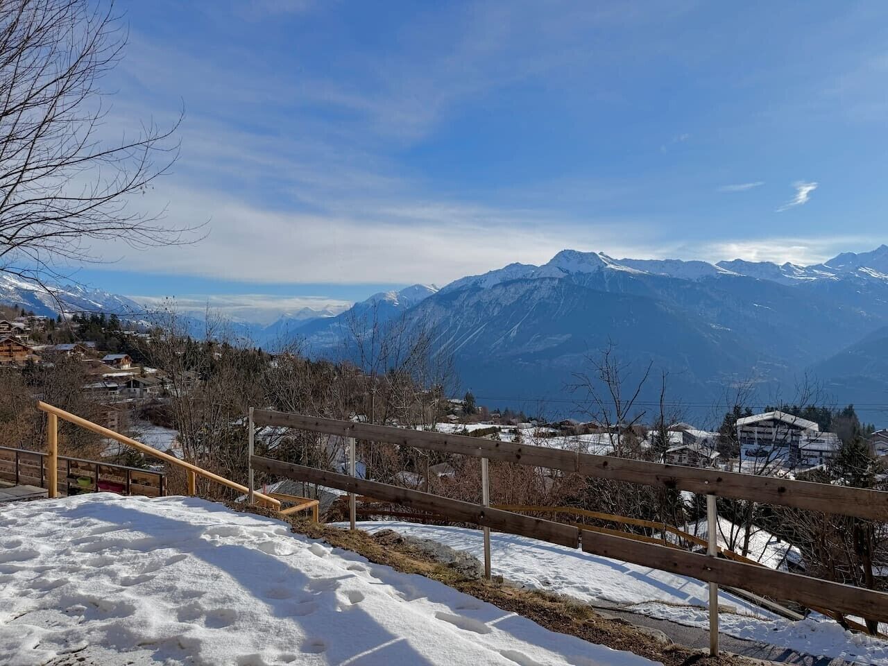 Un paysage enneigé avec une clôture en bois et des bâtiments en arrière-plan.