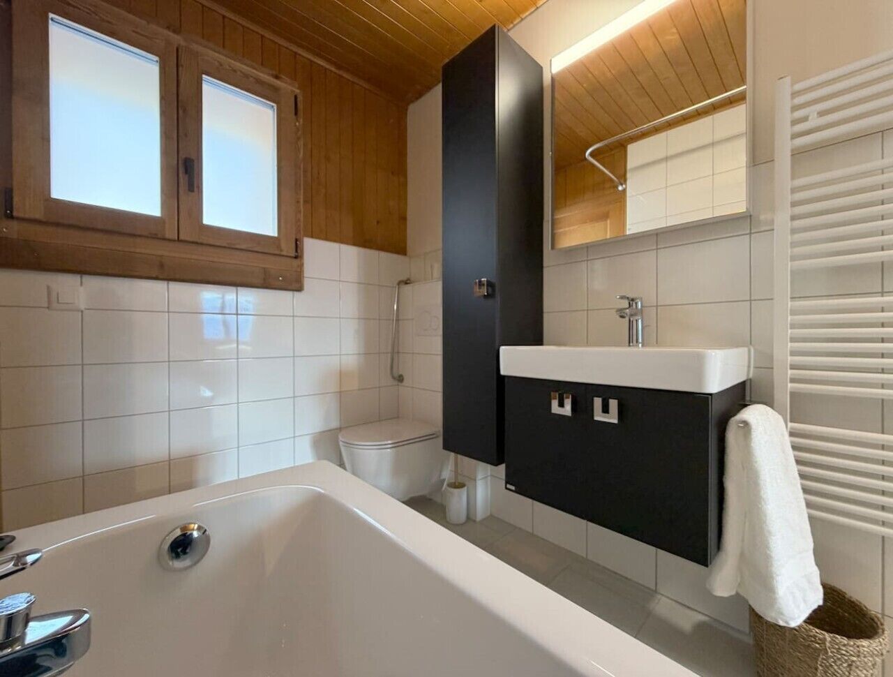 Une salle de bain moderne équipée d’une baignoire, de toilettes et d’un meuble-lavabo avec un miroir.