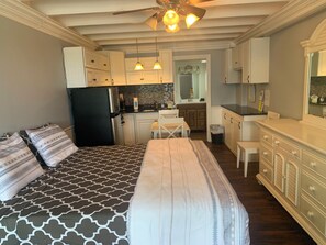 A bedroom with a bed, a desk, and a kitchenette in the background. - #425 Fontainebleau Updated Beachfront Condo (Panama City Beach)