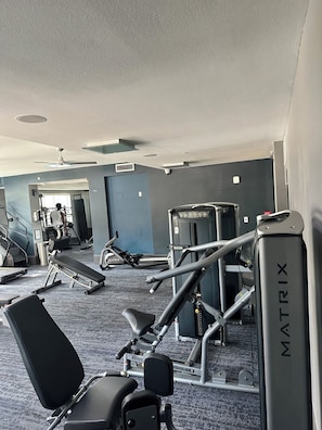 Una palestra con attrezzature per esercizi, un tapis roulant e un condizionatore d'aria a parete.
