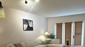 Een moderne woonkamer met een hoekbank, een eettafel en een keuken met granieten aanrechtbladen.
