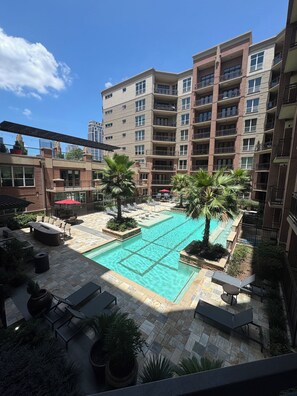 A rooftop pool area with lounge chairs, palm trees, and a view of a multi-story building. - Cozy 1-bedroom apartment with backyard in Postoak/ Galleria Houston (Houston)