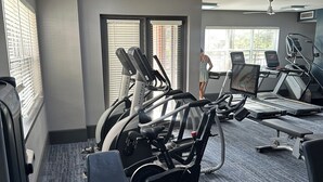 Een sportschool met hometrainers, loopbanden en een plafondventilator.