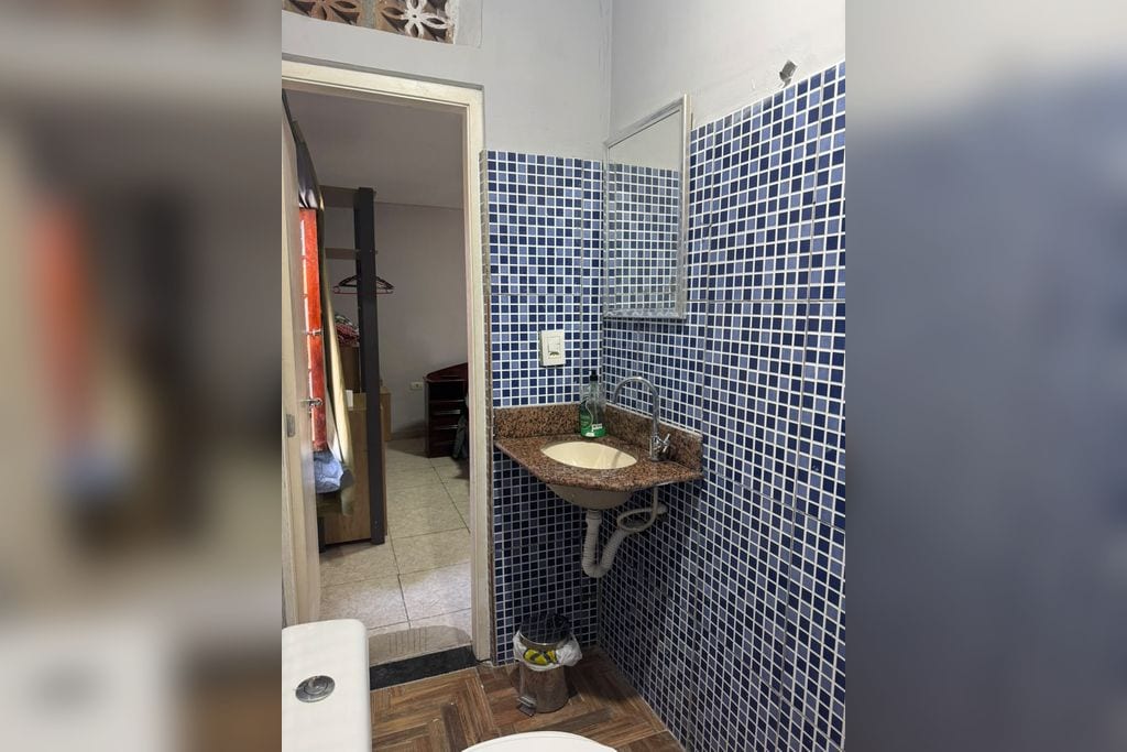 A bathroom with a sink, mirror, and tiled walls.