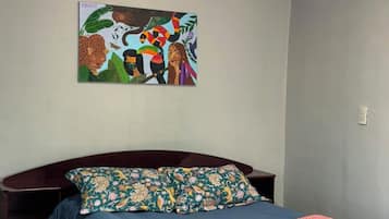 Een slaapkamer met een bed, een aan de muur hangend schilderij en een nachtkastje.