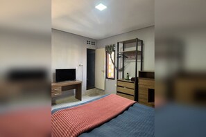 A bedroom with a bed, a desk, a TV, a wardrobe, and a mirror.