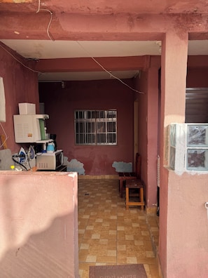 Una habitación con piso de baldosas, una ventana con rejas y un electrodoméstico blanco en la pared.