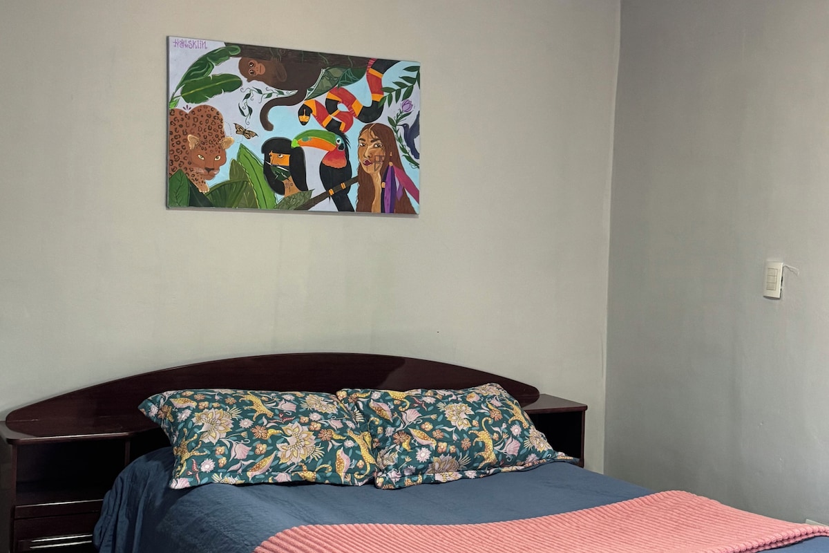 A bedroom with a bed, a nightstand, a dresser, and a wall-mounted painting.