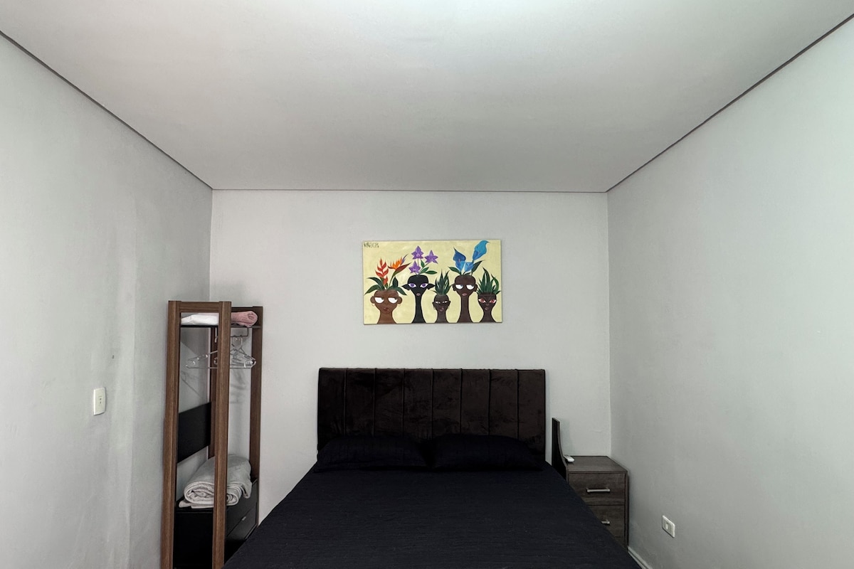 A bedroom with a bed, a nightstand, a wardrobe, and a painting on the wall.