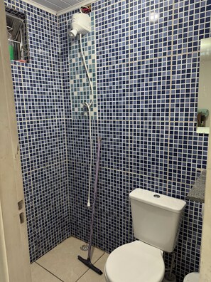 A small bathroom with a toilet, a shower, and a tiled wall. - Gru House - Majohe (Guarulhos)