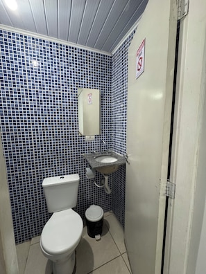 A small bathroom with a toilet, sink, and a trash bin. - Gru House - Majohe (Guarulhos)
