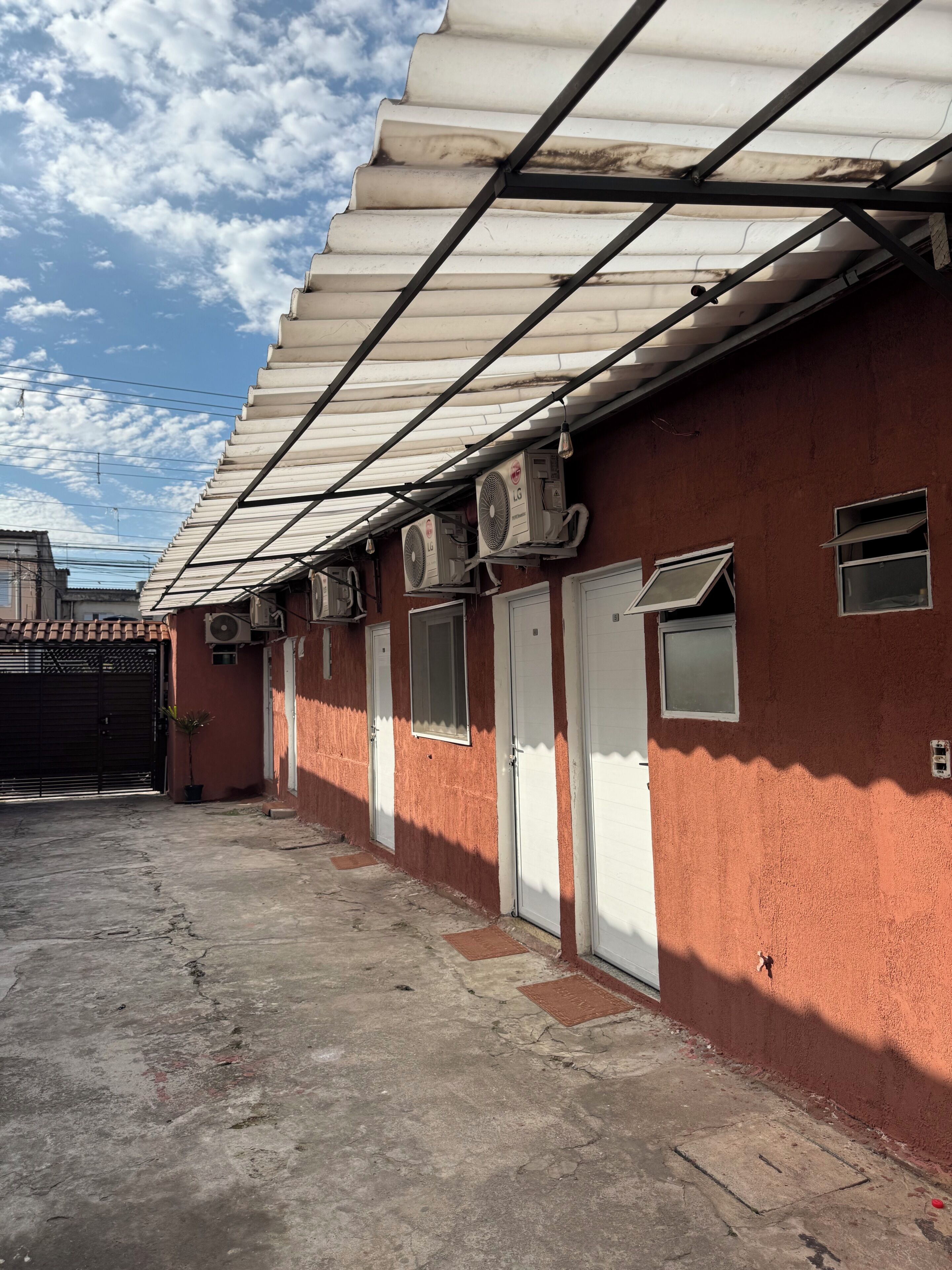 Un edificio con techo de metal corrugado, múltiples unidades de aire acondicionado y varias puertas.