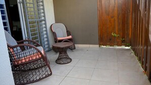 A patio area with two wicker chairs and a small round table, enclosed by a wooden fence. - Residencial corales del sol (Santo Domingo Este)