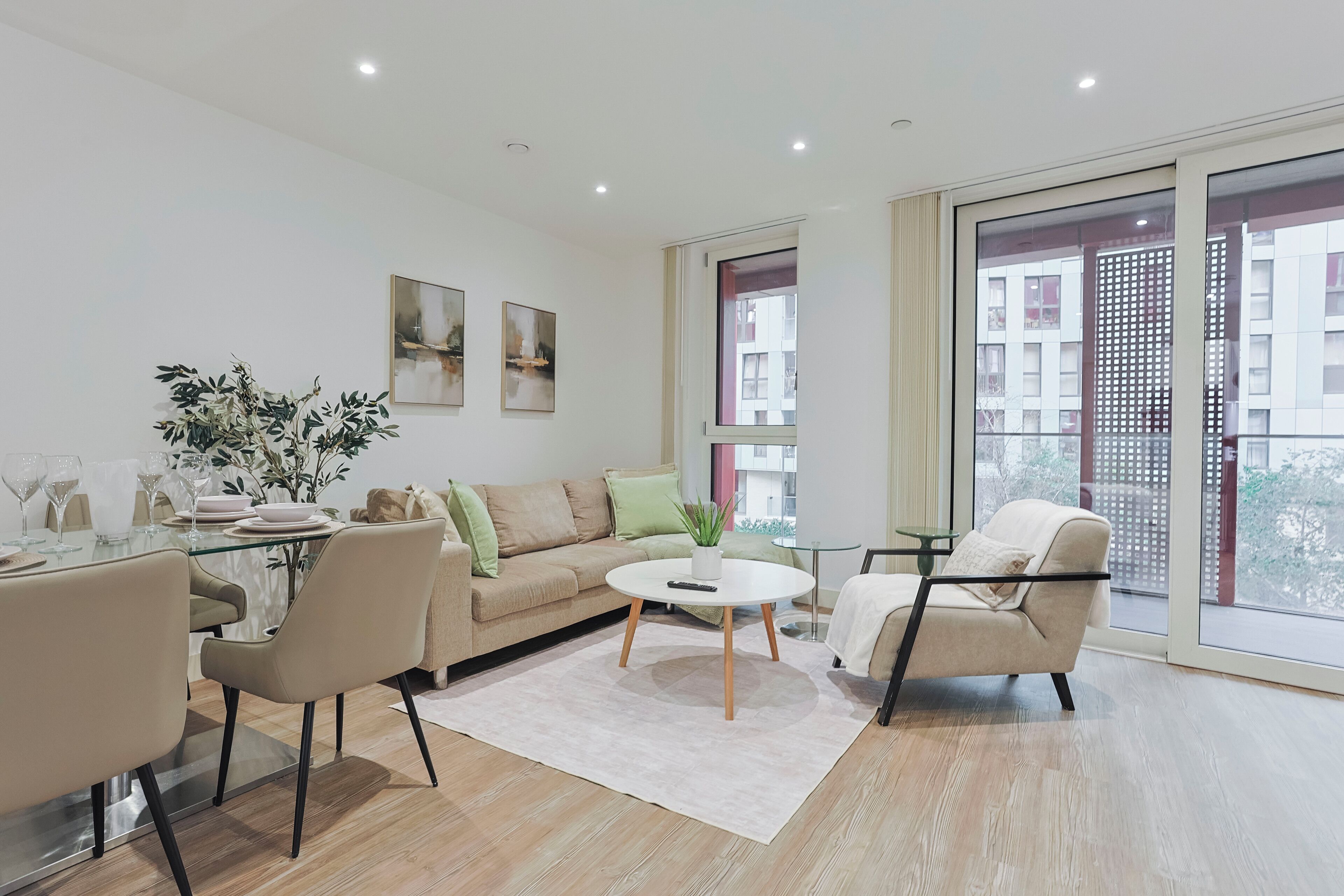 Un salon moderne comprenant un canapé, des fauteuils, une table basse et un coin repas avec une table et des chaises en verre.