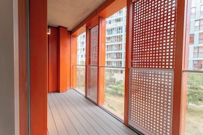 A corridor with a patterned floor, red walls, and a view of a building with multiple windows. - Luxury 2-Bed Greenwich Apartment with River Views & Private Balcony (London)