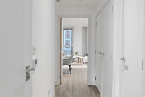 A modern hallway leading to a dining area with a view of the outside. - Luxury 2-Bed Greenwich Apartment with River Views & Private Balcony (London)