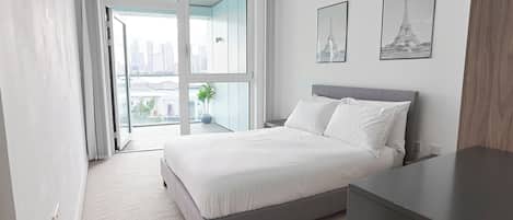 A modern bedroom with a large bed, a nightstand, a dresser, and two framed pictures of the Eiffel Tower.