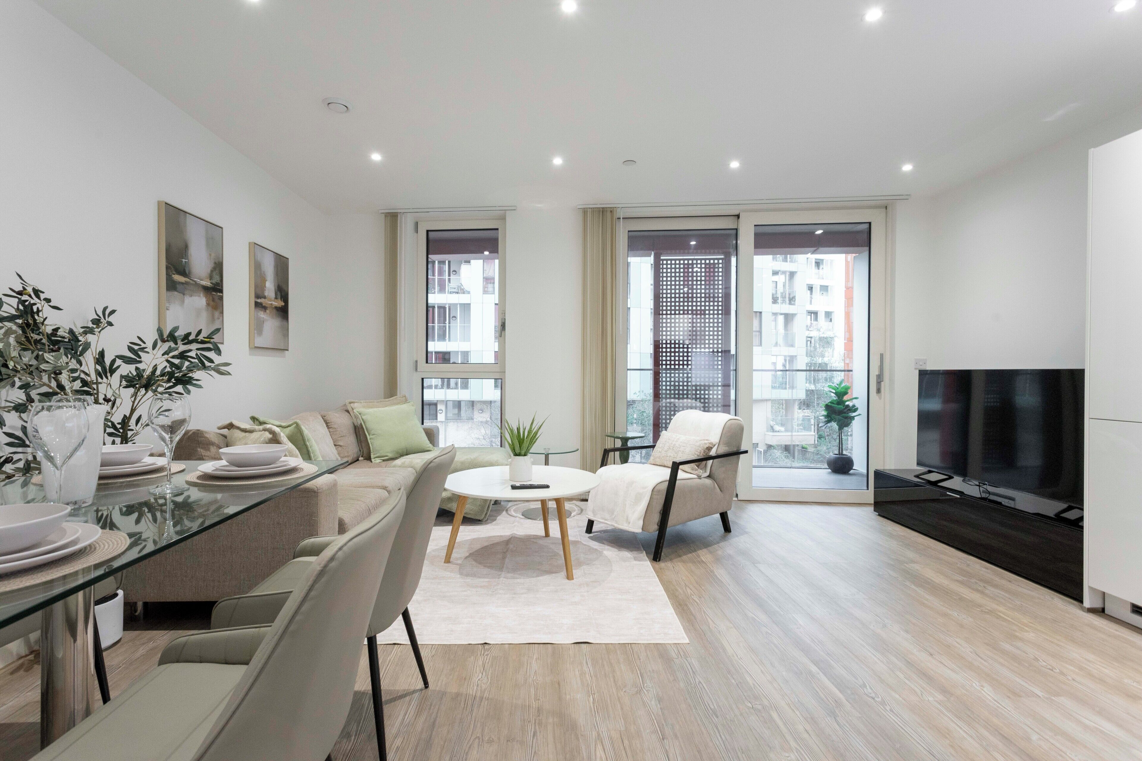 Ein modernes Wohnzimmer mit einem Glastisch, einer Couch, einem Sessel und einem Fernseher.