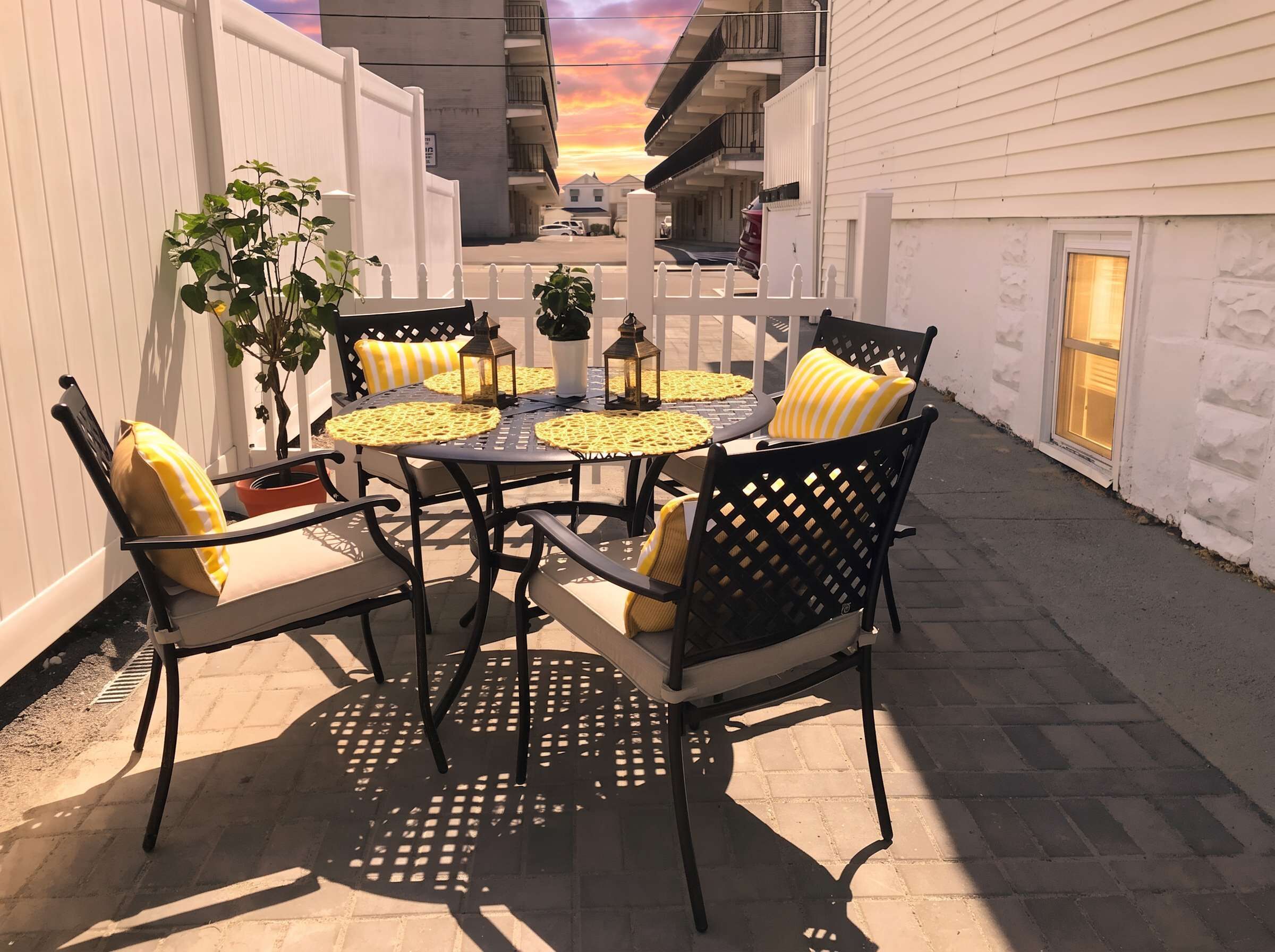 An outdoor patio with a round table, four chairs, and potted plants.