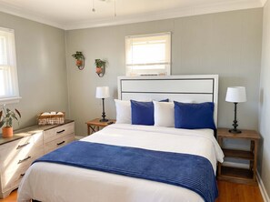 A bedroom with a bed, bedside tables, lamps, a nightstand, a dresser, and two wall-mounted plants. - Unit 3 - Cozy 2 Bedroom Apartment Near Seaside Beach & Boardwalk (Seaside Heights)
