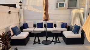 Una terraza con mobiliario exterior, incluyendo sofás y mesas, y una pérgola con sombrilla.