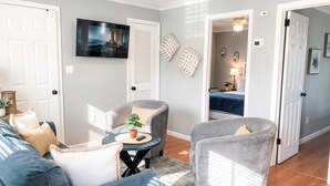 Una sala de estar con un sofá, sillones, una mesa de centro y una televisión.