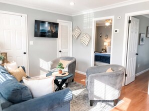 Ein Wohnzimmer mit einer Couch, Sesseln, einem Couchtisch und einem Fernseher.