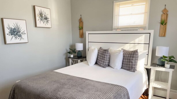Un dormitorio con cama, mesitas de noche, lámparas y decoración en la pared.
