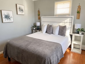 A bedroom with a bed, bedside tables, lamps, and wall art. - Unit 3 - Cozy 2 Bedroom Apartment Near Seaside Beach & Boardwalk (Seaside Heights)