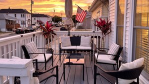Eine Terrasse mit Gartenmöbeln, eine amerikanische Flagge und Blick auf die Straße bei Sonnenuntergang.