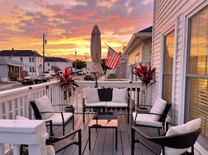 Eine Terrasse mit Gartenmöbeln, eine amerikanische Flagge und Blick auf die Straße bei Sonnenuntergang.