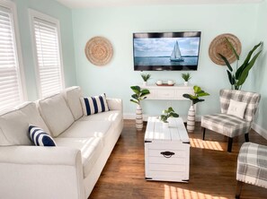 Ein Wohnzimmer mit Sofa, Sesseln, einem Couchtisch, einem Fernseher und Dekorationselementen.