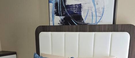 A bed with a quilted blue cover, a matching pillow, and a dark brown headboard.
