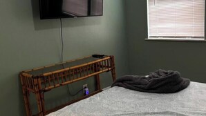 A room with a bed, a television mounted on the wall, and a window with blinds. - Downtown SRQ 3BR 2ba, Playground, Unit 1, Sleeps 6 (Sarasota)
