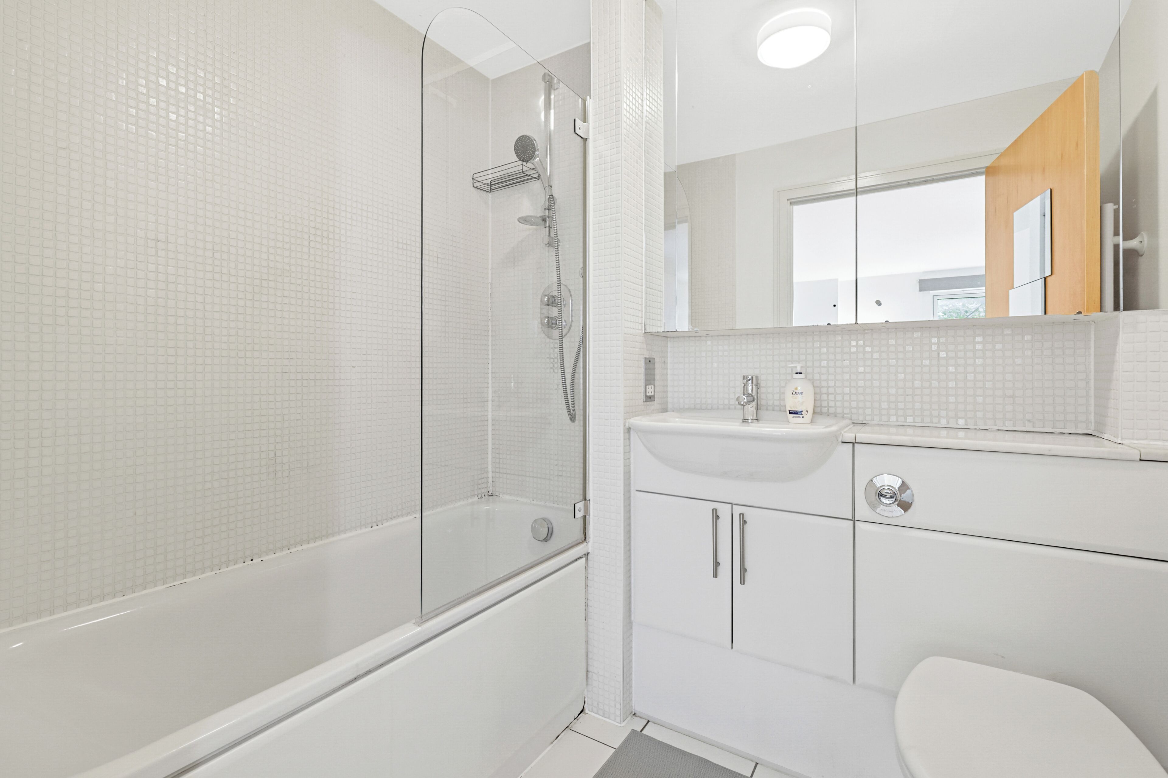 A modern bathroom with a glass-enclosed shower, a white sink, and a mirror above the vanity.