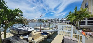 A marina with boats docked, a flag, and waterfront buildings. - Most Photographed Bayfront-Amazing Sunset & Palm Trees on Exclusive Snug Harbor! (Stone Harbor)