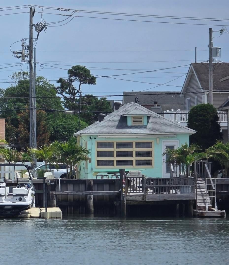 Una casa azul claro con techo a dos aguas, un muelle y un barco amarrado cerca.