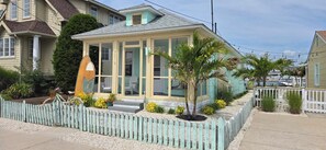 A coastal house with a conservatory, a wooden fence, and a small garden with palm trees. - Most Photographed Bayfront-Amazing Sunset & Palm Trees on Exclusive Snug Harbor! (Stone Harbor)