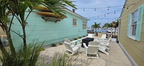 A turquoise building with outdoor seating, a table, and chairs. - Most Photographed Bayfront-Amazing Sunset & Palm Trees on Exclusive Snug Harbor! (Stone Harbor)