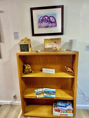 Une étagère en bois avec un tableau encadré, un livre intitulé « Mines, minéraux, mustangs » et une pancarte « Détendez-vous ».