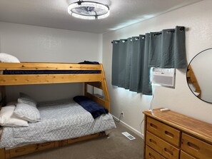 A bunk bed with a headboard, a dresser with drawers, a wall-mounted heater, and a window with curtains. - 7-Min Down Town Reno & UNR 35 Min to MtRoseSki & Walking Distance to the Rodeo. (Reno)