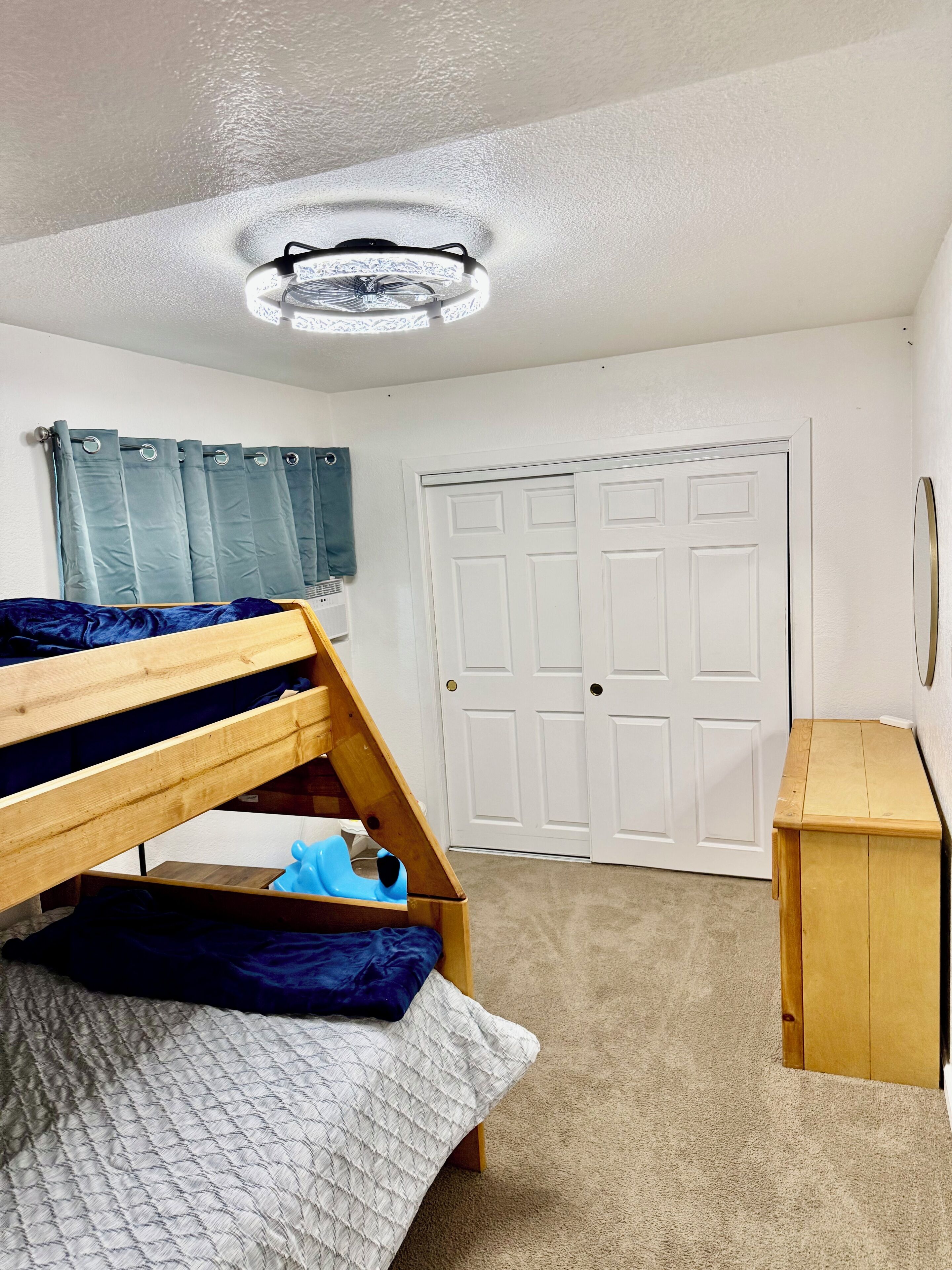 A room with a bunk bed, a desk, a wardrobe, and a door.