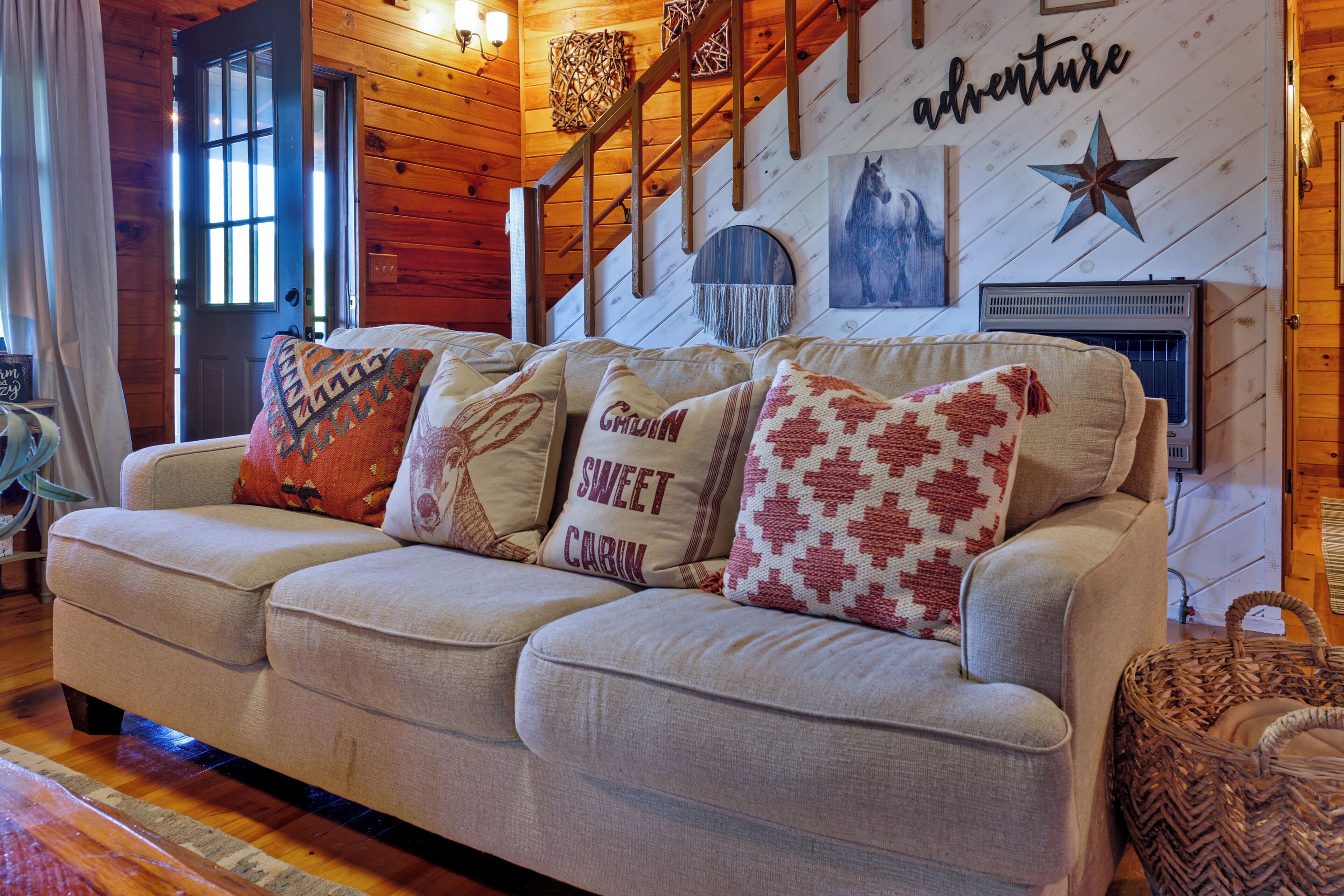 A cozy living room with a wooden staircase, a fireplace, and a wall with a star decoration.