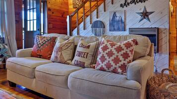 A cozy living room with a wooden staircase, a fireplace, and a wall with a star decoration.
