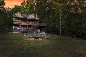 A two-story house with a deck, outdoor seating, and a fire pit. - Rustic Cottage in Blue Ridge: Hot Tub • Mtn Views • Pets • Fire Pit • EV Charger (Mineral Bluff)