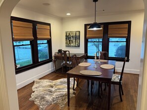 A dining area with a wooden table, chairs, and a rug. - 3 bedroom charming Heights cottage for relaxing under the trees (Houston)