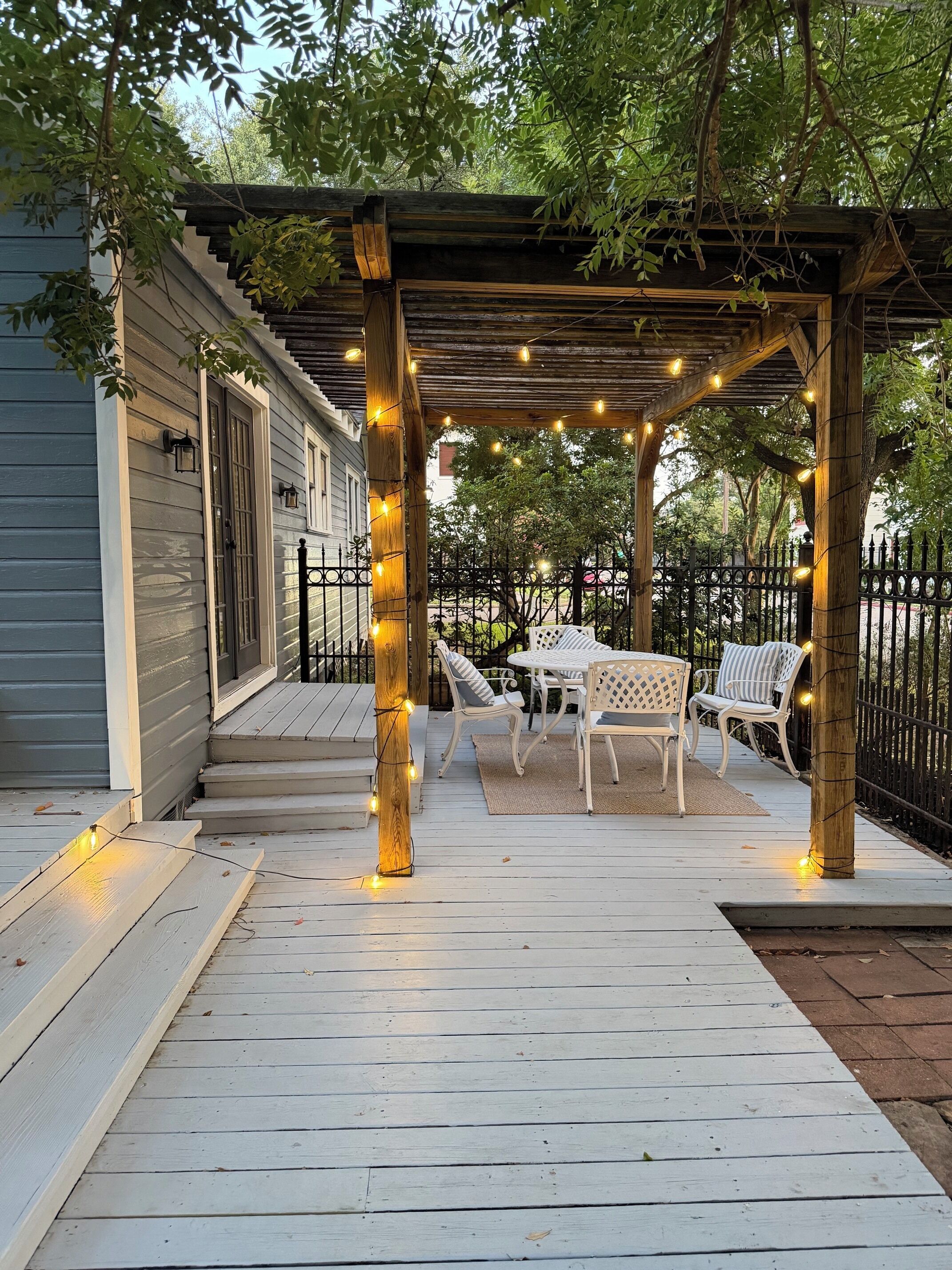 A wooden deck with a pergola, string lights, and outdoor furniture.