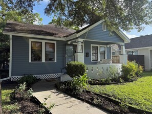A residential house with a front porch, a mailbox, and a well-maintained lawn. - 3 bedroom charming Heights cottage for relaxing under the trees (Houston)